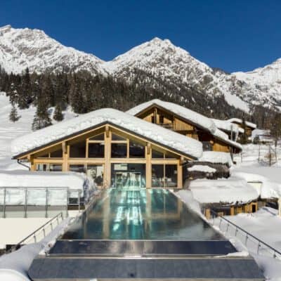 Sky Infinity Pool vor den verschneiten Dolomiten im Almwellness Resort Tuffbad