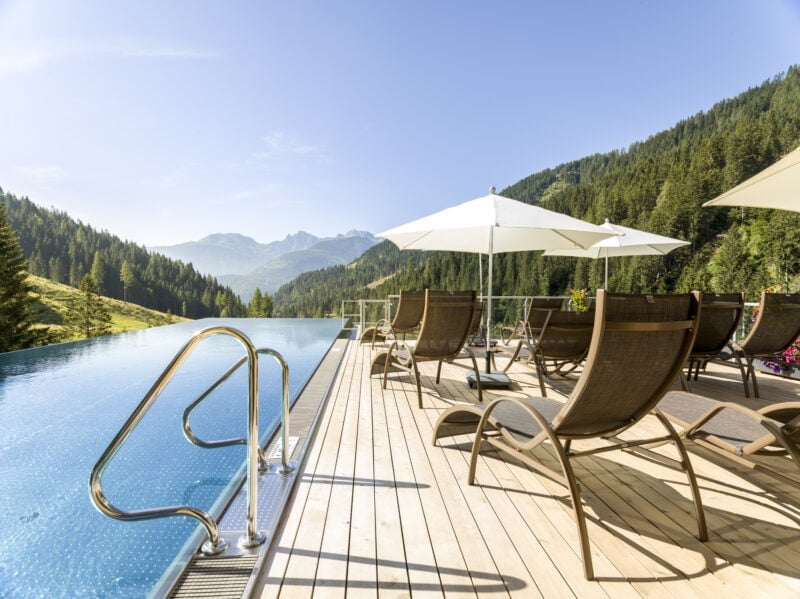 Traumhafter Ausblick auf die grüne Bergwelt vom Infinity Pool des Almwellness-Resort Tuffbad
